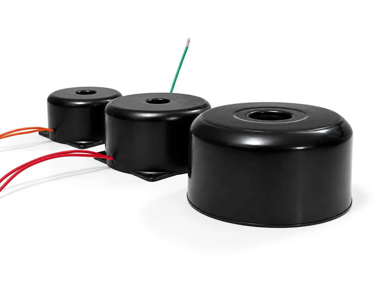 Farklı ölçülerde üç siyah plastik kapaklı toroidal transformatör